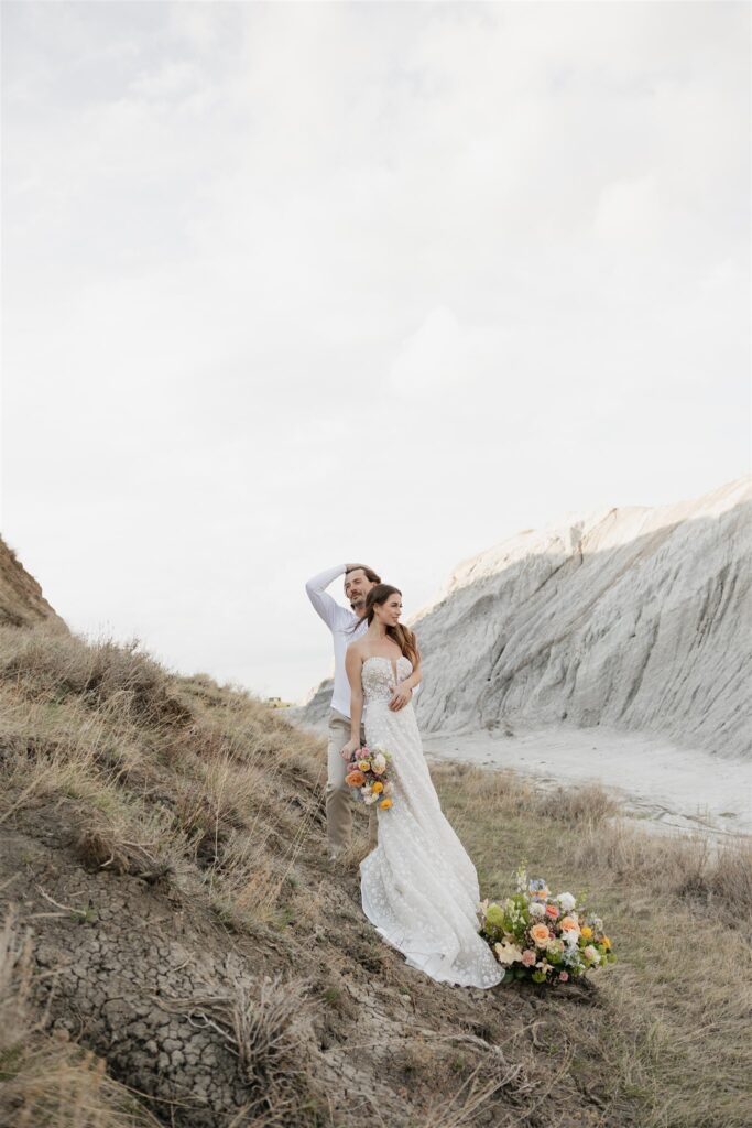 a young couple posing for their wedding photos in saskatchewan with colorful wedding flowers
