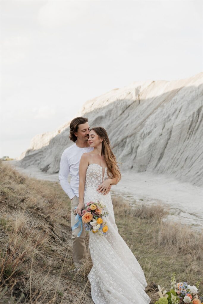 a young couple posing for their wedding photos in saskatchewan with colorful wedding flowers
