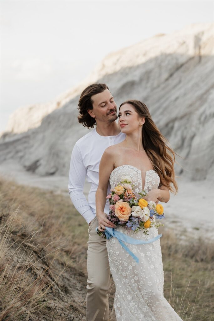 a young couple posing for their wedding photos in saskatchewan with colorful wedding flowers