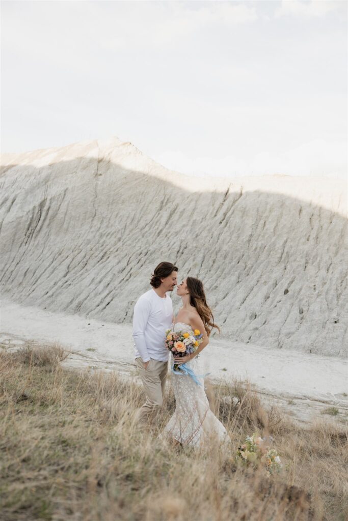 a young couple posing for their wedding photos in saskatchewan with colorful wedding flowers
