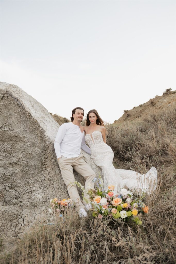 a young couple posing for their wedding photos in saskatchewan with colorful wedding flowers
