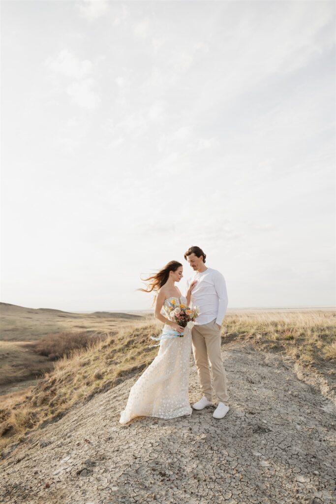 a young couple posing for their wedding photos in saskatchewan with colorful wedding flowers