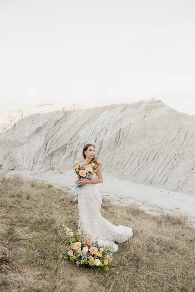 a young couple posing for their wedding photos in saskatchewan with colorful wedding flowers
