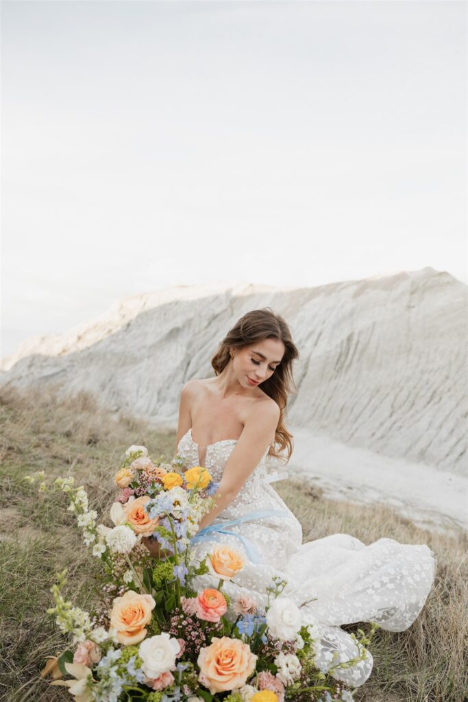 a young couple posing for their wedding photos in saskatchewan with colorful wedding flowers
