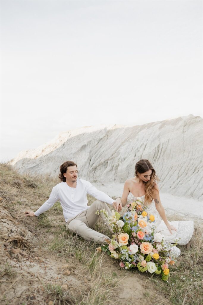 a young couple posing for their wedding photos in saskatchewan with colorful wedding flowers
