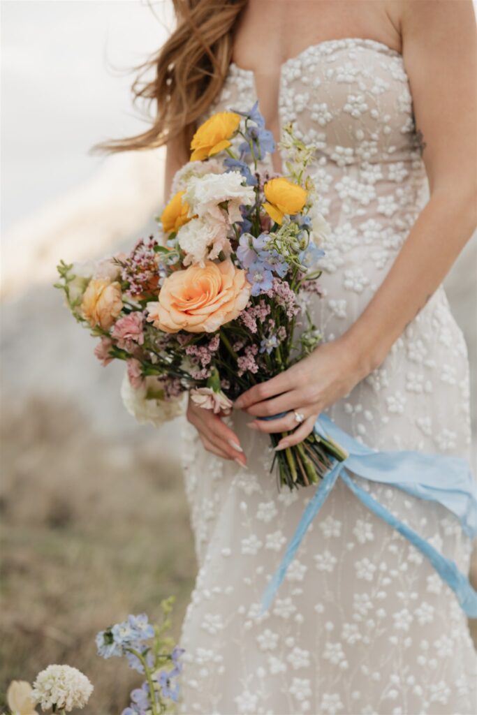 a young couple posing for their wedding photos in saskatchewan with colorful wedding flowers
