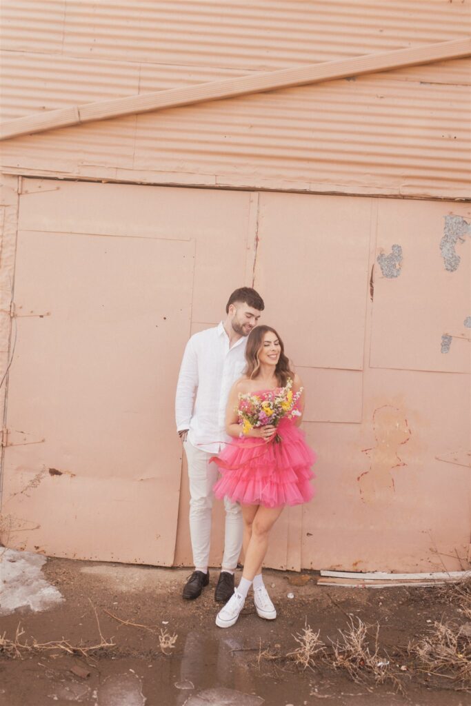 couple posing for their downtown saskatoon photoshoot in bright colored clothes
