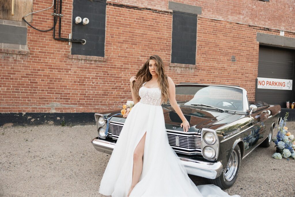 couple posing with a vintage car for their urban wedding photos
