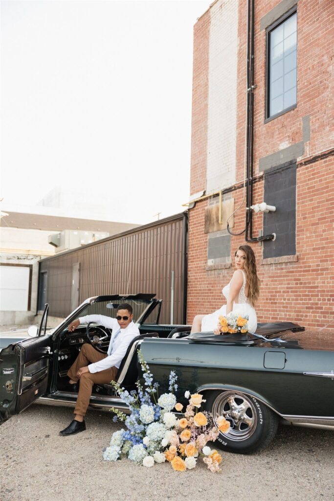 couple posing with a vintage car for their urban wedding photos