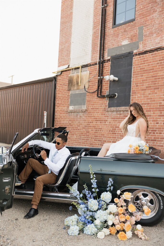 couple posing with a vintage car for their urban wedding photos | Modern Editorial Wedding Photos in Downtown Saskatoon
