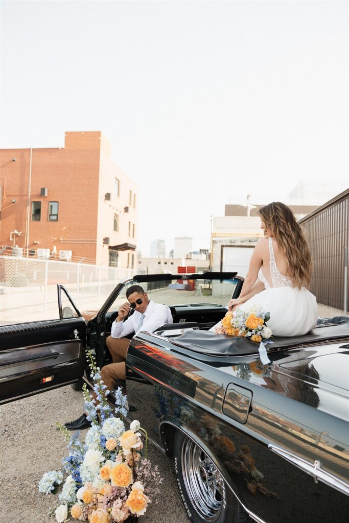 couple posing with a vintage car for their urban wedding photos
