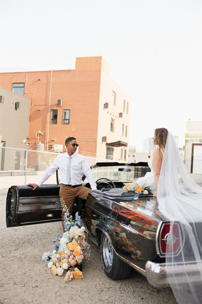 couple posing with a vintage car for their urban wedding photos
