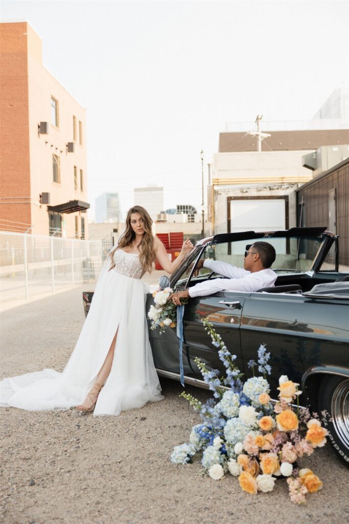 couple posing with a vintage car for their urban wedding photos
