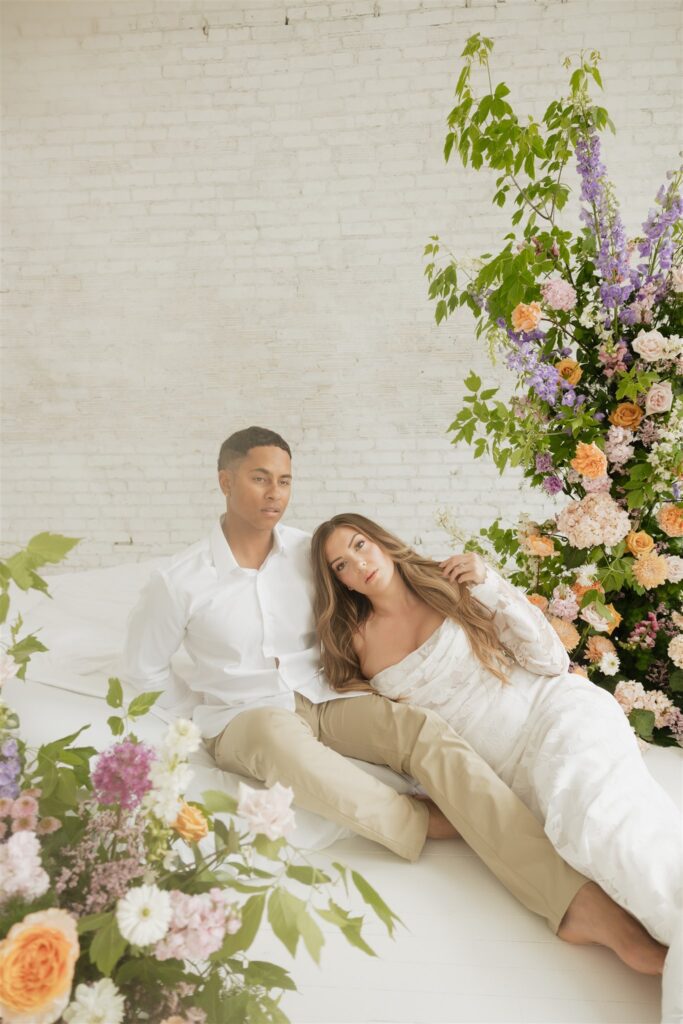 bride and groom posing in a white studio with bright wedding flowers and bouquet
