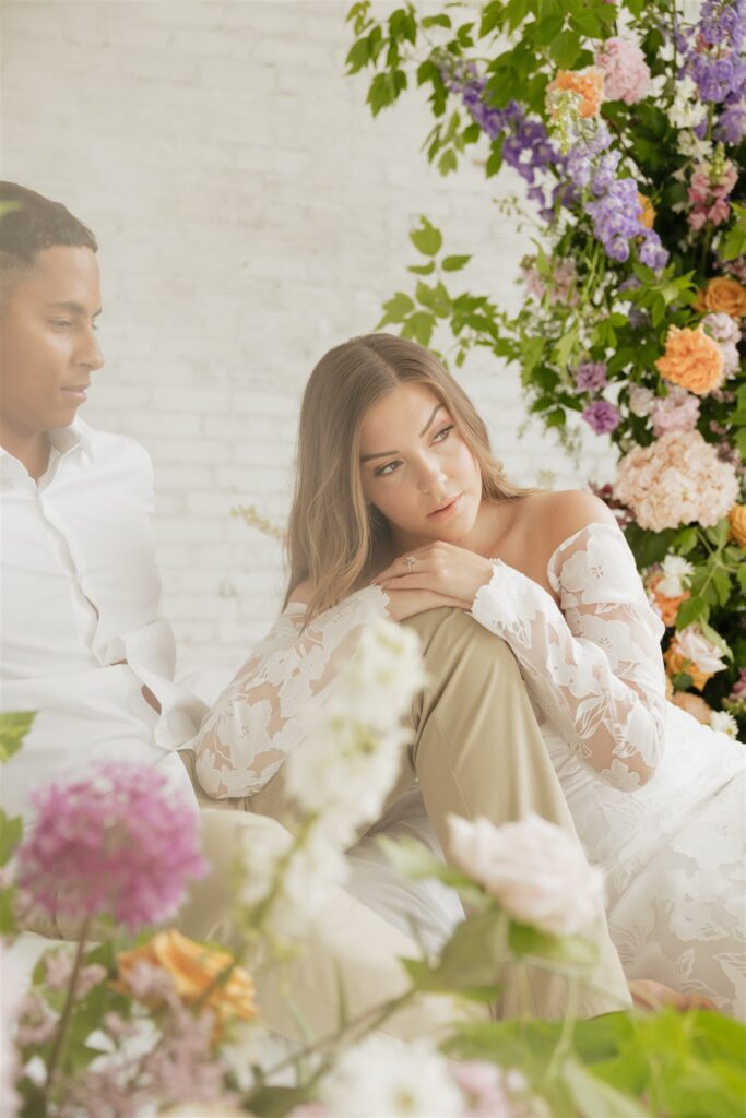 bride and groom posing in a white studio with bright wedding flowers and bouquet
