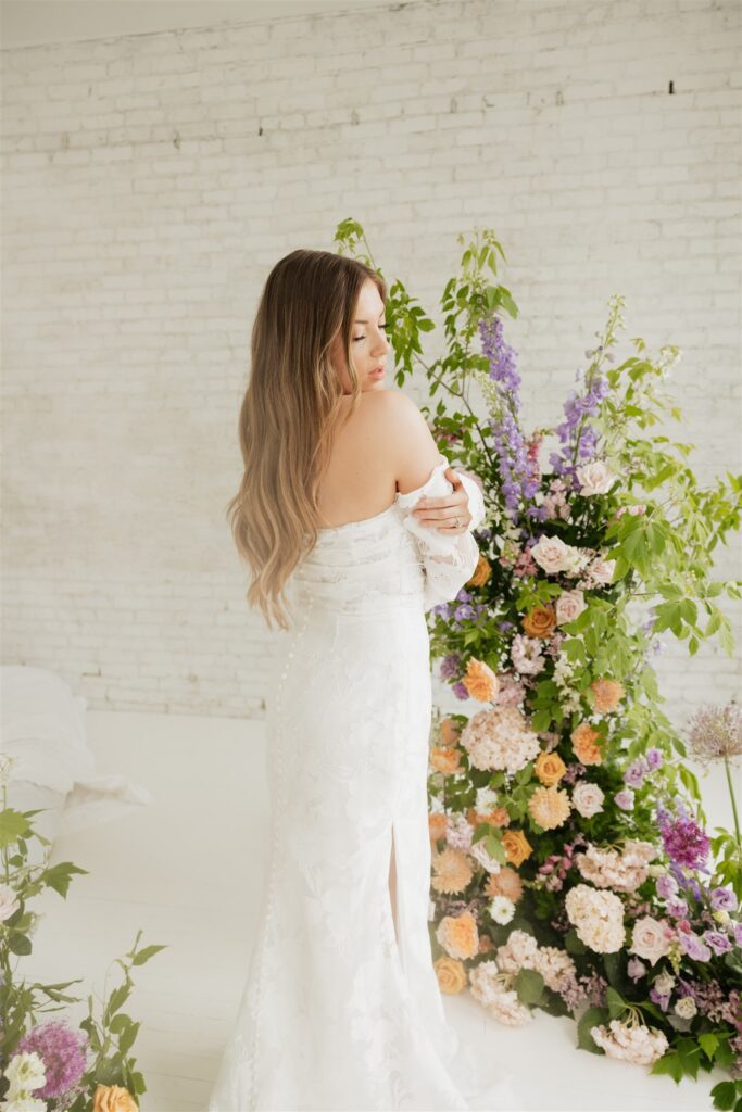 bride and groom posing in a white studio with bright wedding flowers and bouquet
