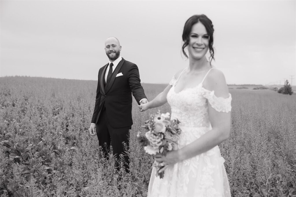 bride and groom posing in a field in saskatoon