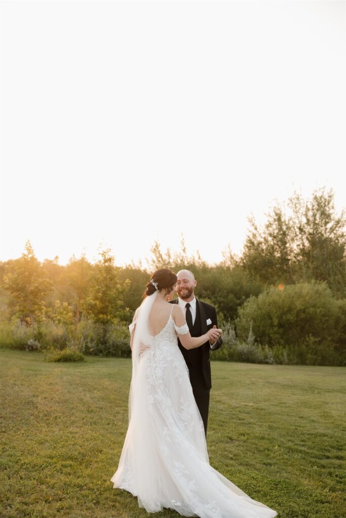 bride and groom posing in a field in saskatoon