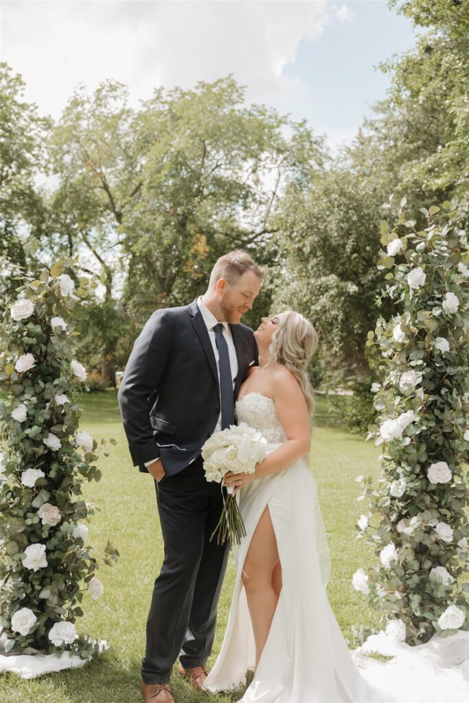 bride and groom posing in a field in canada for their wedding portraits