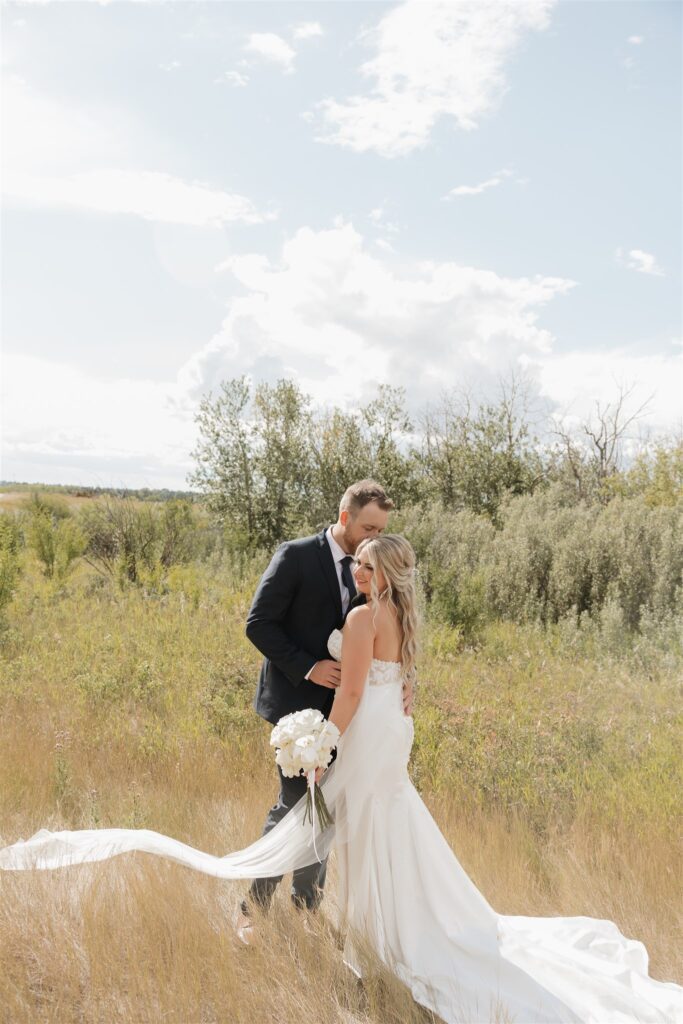 bride and groom posing in a field in canada for their wedding portraits
