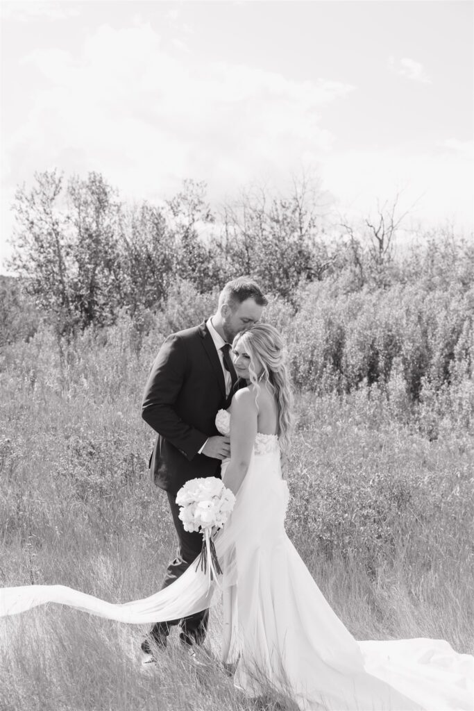 bride and groom posing in a field in canada for their wedding portraits
