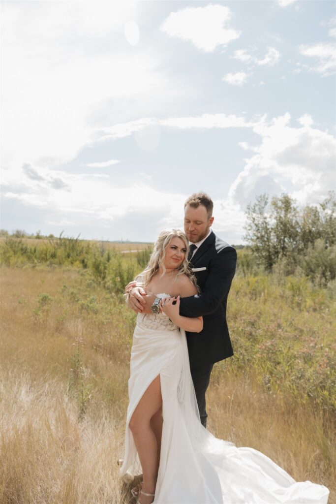 bride and groom posing in a field in canada for their wedding portraits
