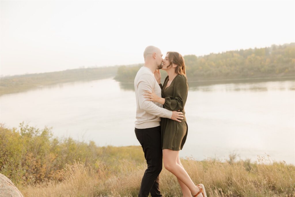 couple taking engagement photos in an open field
