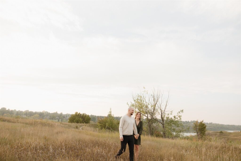 couple taking engagement photos in an open field
