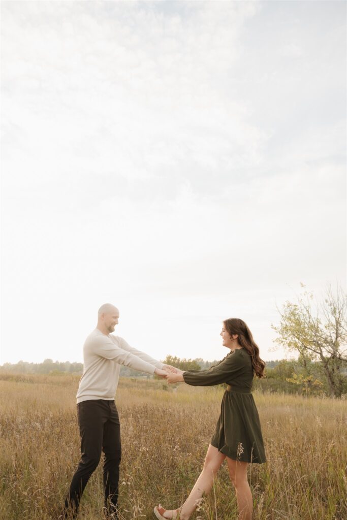 couple posing in a field for their engagement photoshoot
