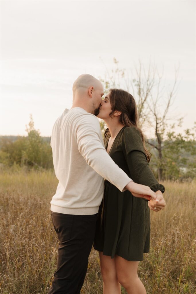 couple taking engagement photos in an open field