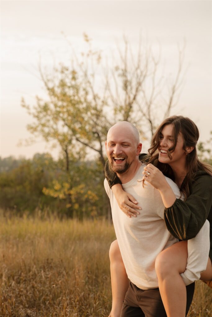 couple taking engagement photos in an open field
