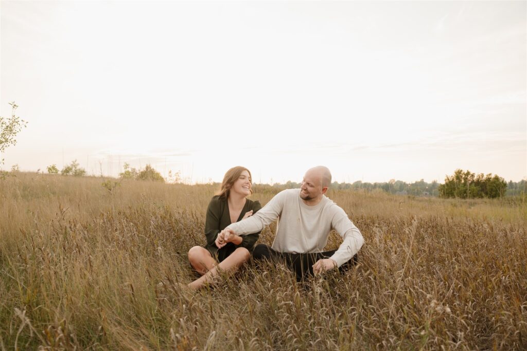 couple taking engagement photos in an open field
