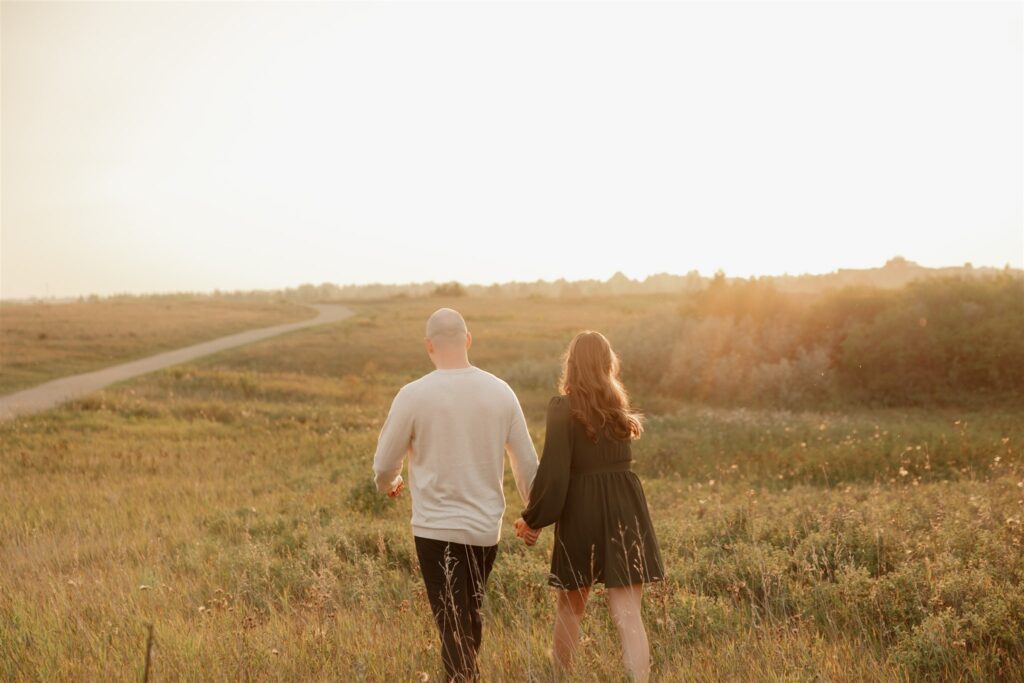 couple taking engagement photos in an open field
