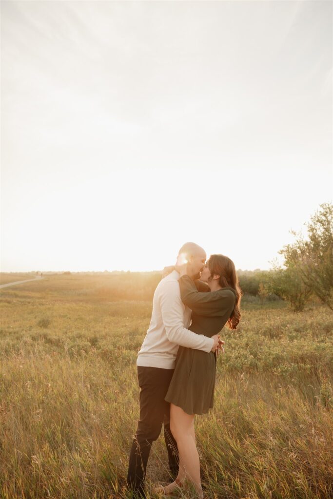 couple taking engagement photos in an open field
