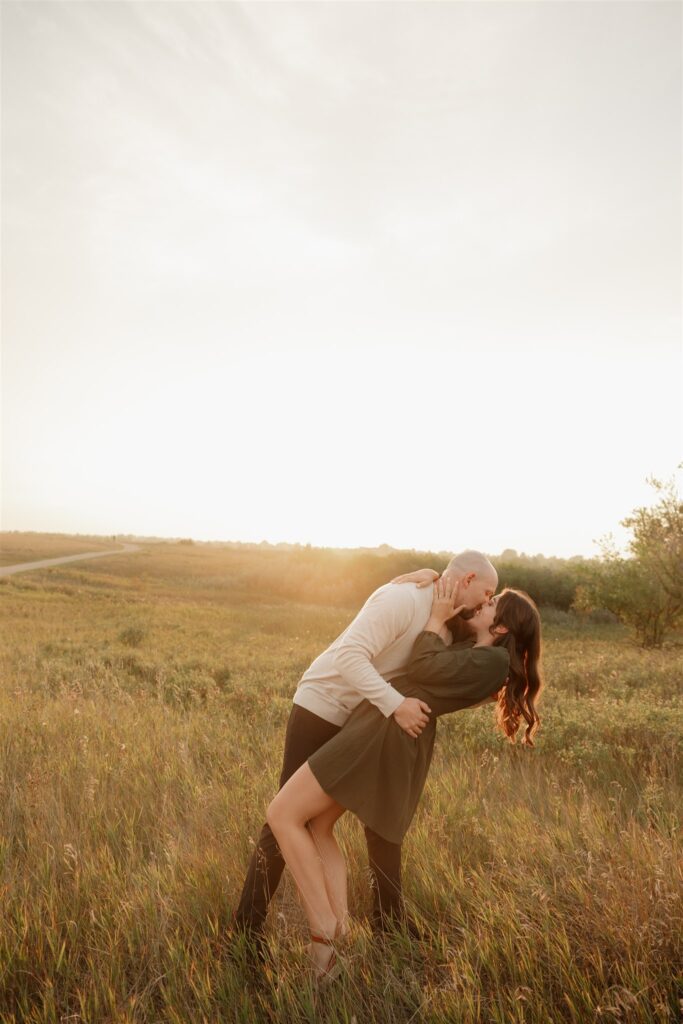 couple playing in a field during golden hour for their engagement photos