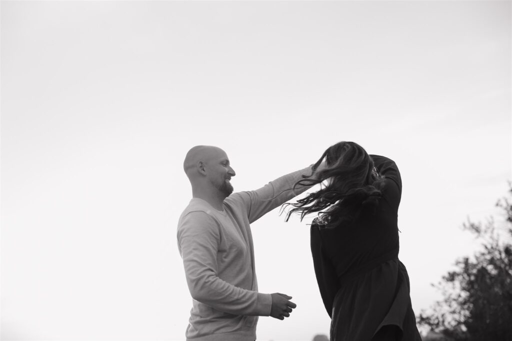 couple playing in a field during golden hour for their engagement photos