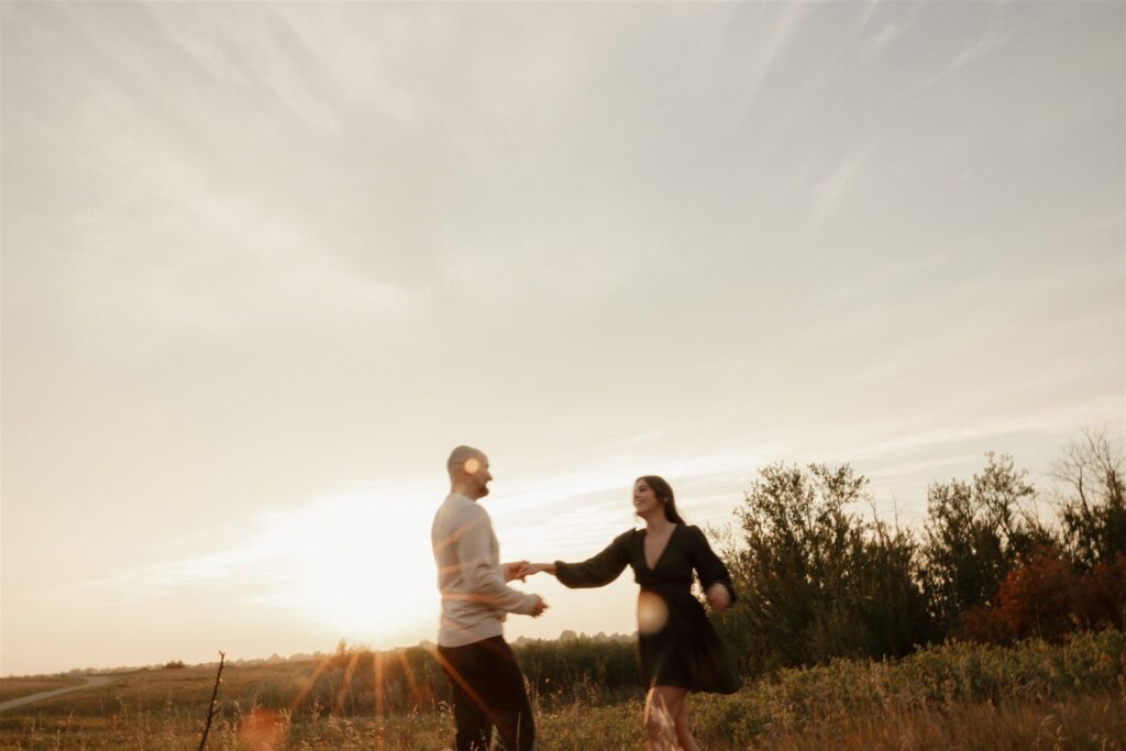 couple taking engagement photos in an open field
