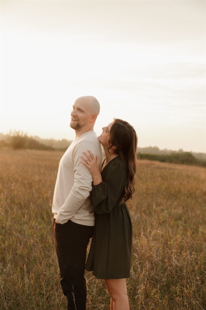 couple playing in a field during golden hour for their engagement photos