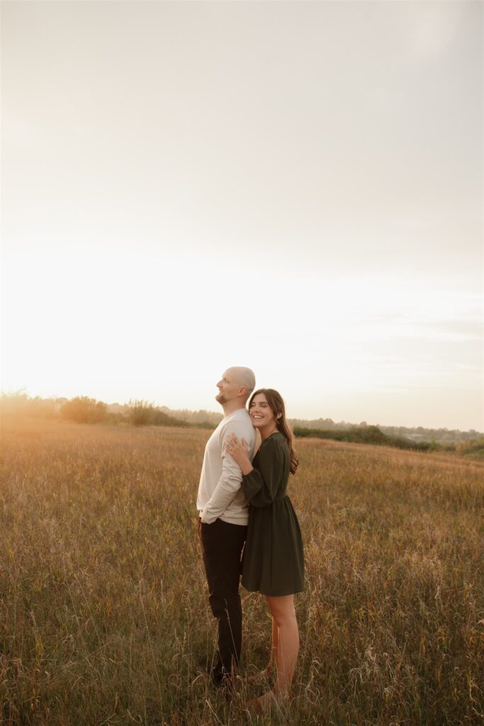 couple playing in a field during golden hour for their engagement photos