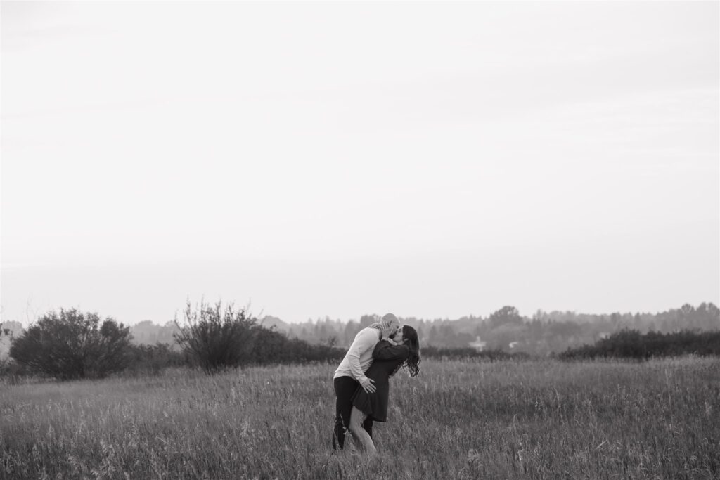 couple posing in a field for their engagement photoshoot
