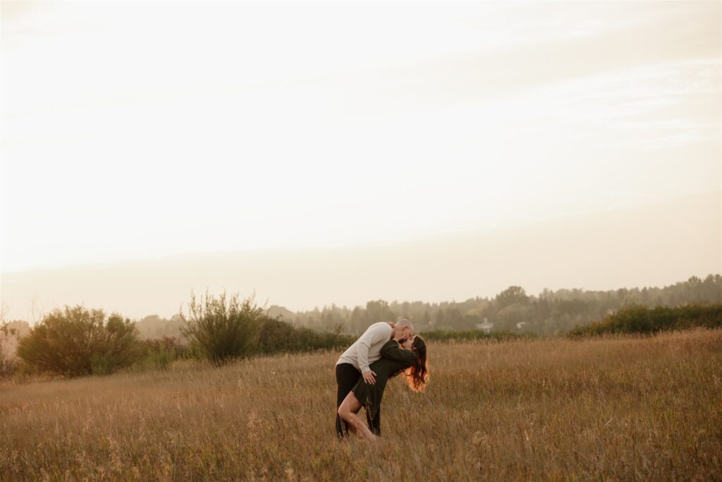 couple posing in a field for their engagement photoshoot
