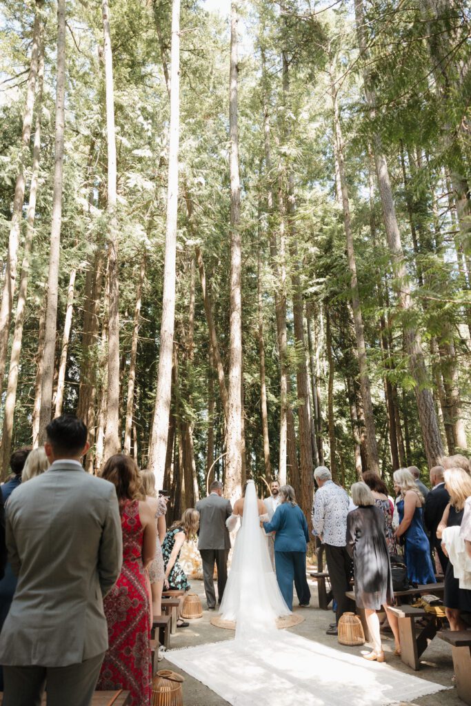 Bride walking down the aisle to her romantic forrest wedding ceremony.