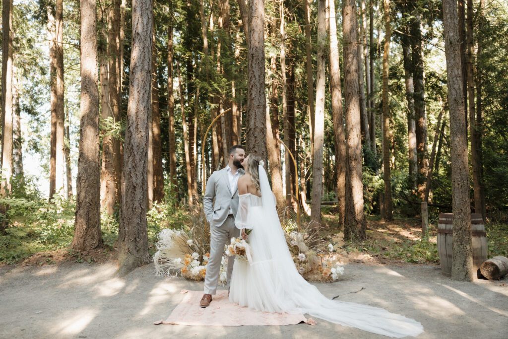 Bride and groom posing in a romantic forrest to capture elegant wedding photos.