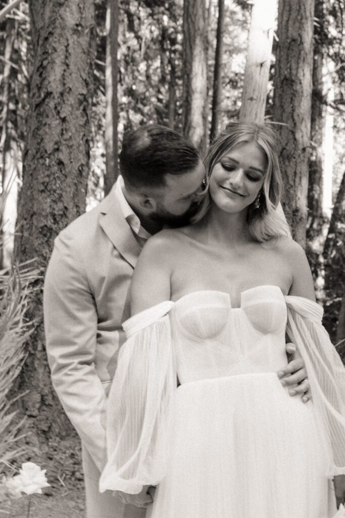 Bride and groom posing in a romantic forrest to capture elegant wedding photos.