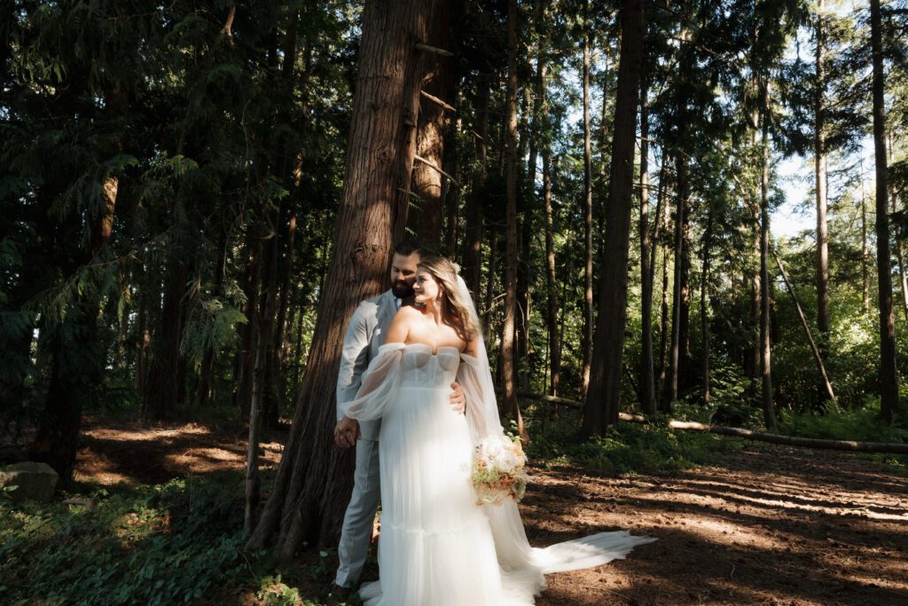 Bride and groom posing in a romantic forrest to capture elegant wedding photos.