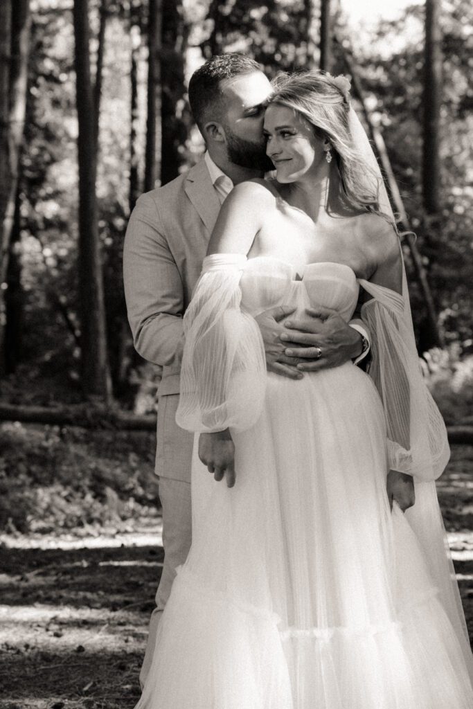 Bride and groom posing in a romantic forrest to capture elegant wedding photos.