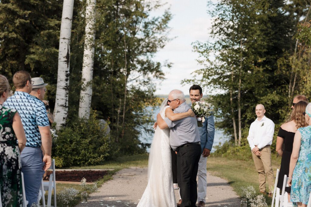 Bride walking down the isle at their lakeside wedding ceremony in Candle Lake Saskatchewan