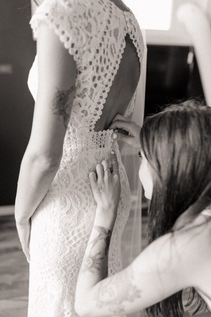 Bride's sister helping her get ready for her woodland fairytale wedding day