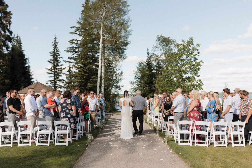 Bride walking down the isle at their lakeside wedding ceremony in Candle Lake Saskatchewan