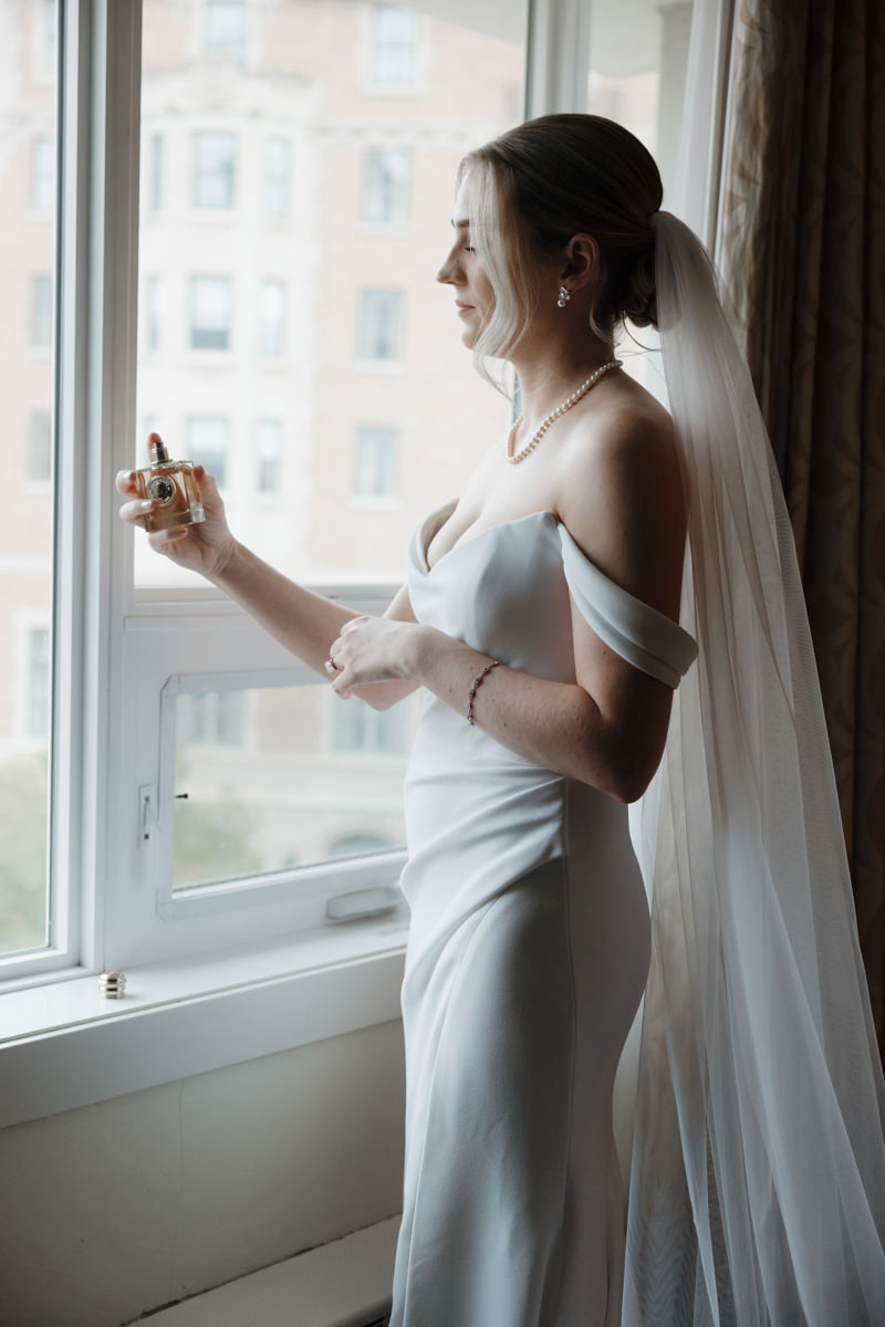 Bride getting ready at Sheraton Cavalier Saskatoon Hotel, wearing a timeless Alyssa Kristin wedding dress, with natural glam by Free Bird Hair Design